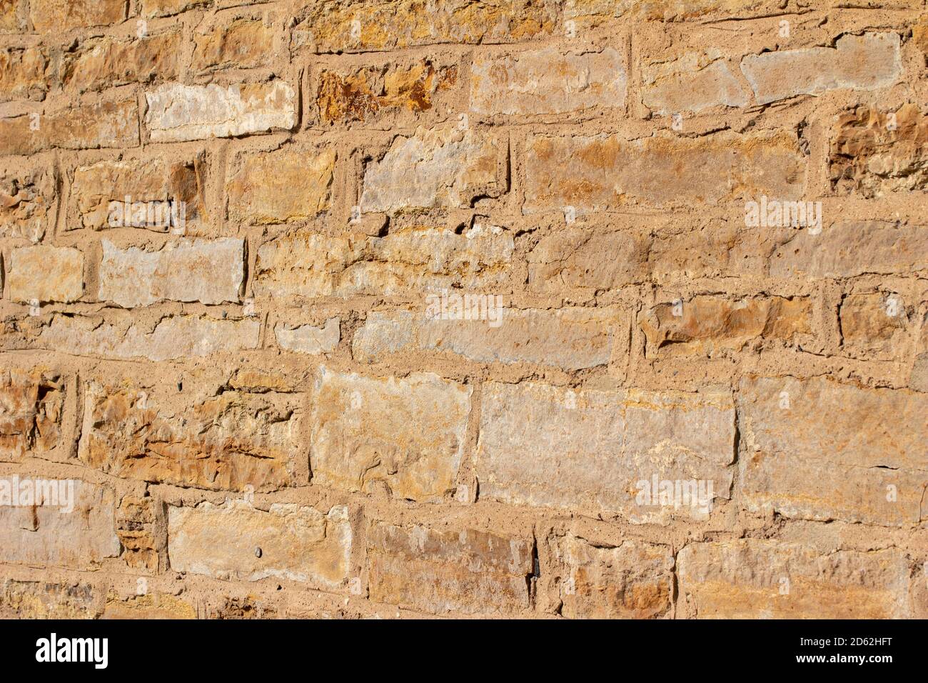 Antique golden brown color stone wall background with worn texture in full sunlight, with copy space Stock Photo