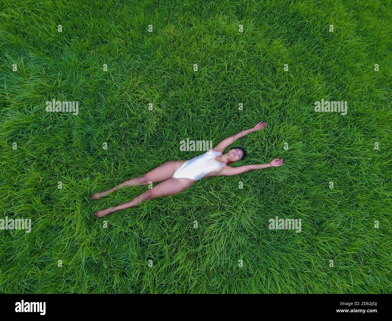 Woman meditating in an empty grass field. Stock Photo