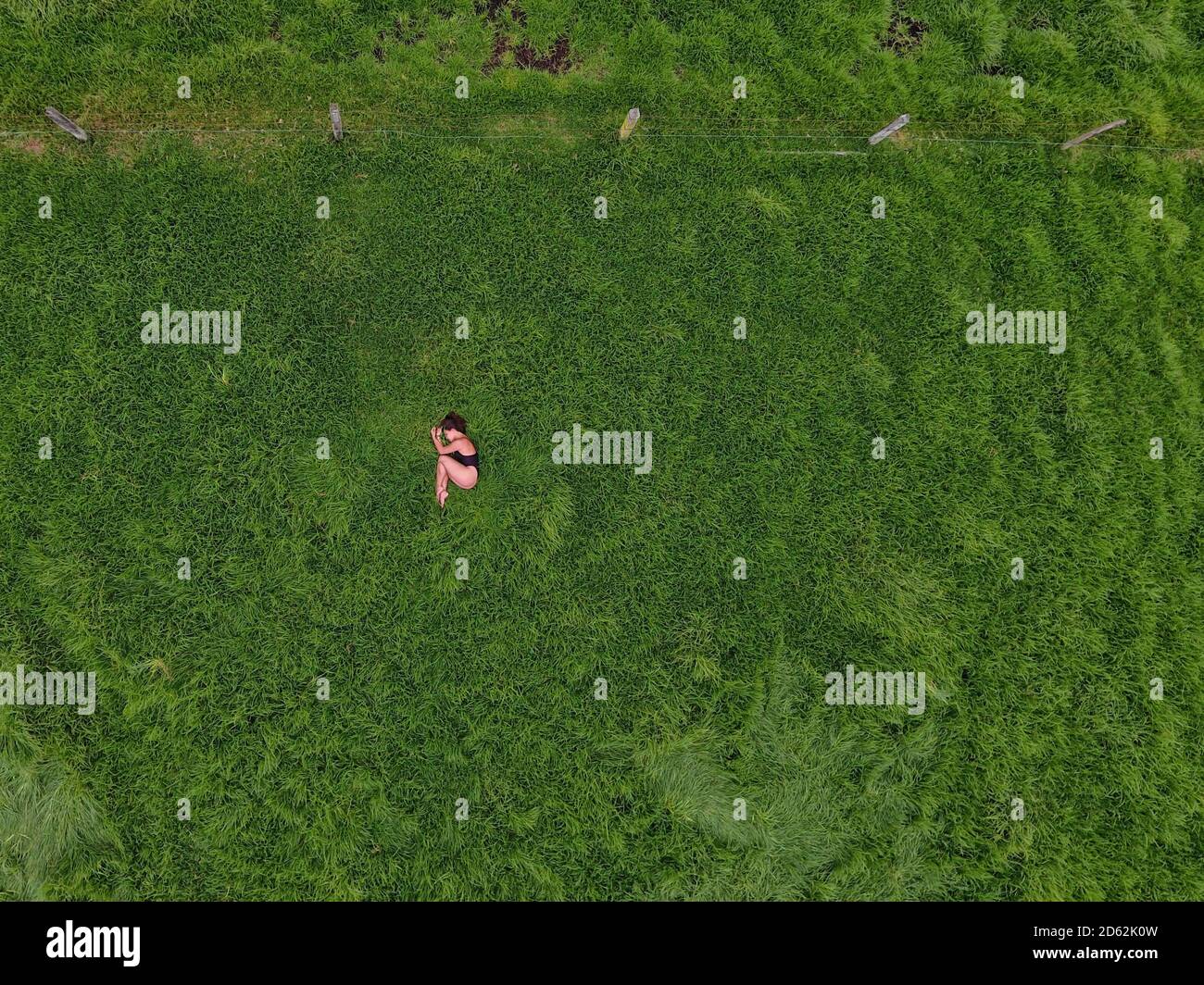 Woman meditating in an empty grass field. Stock Photo
