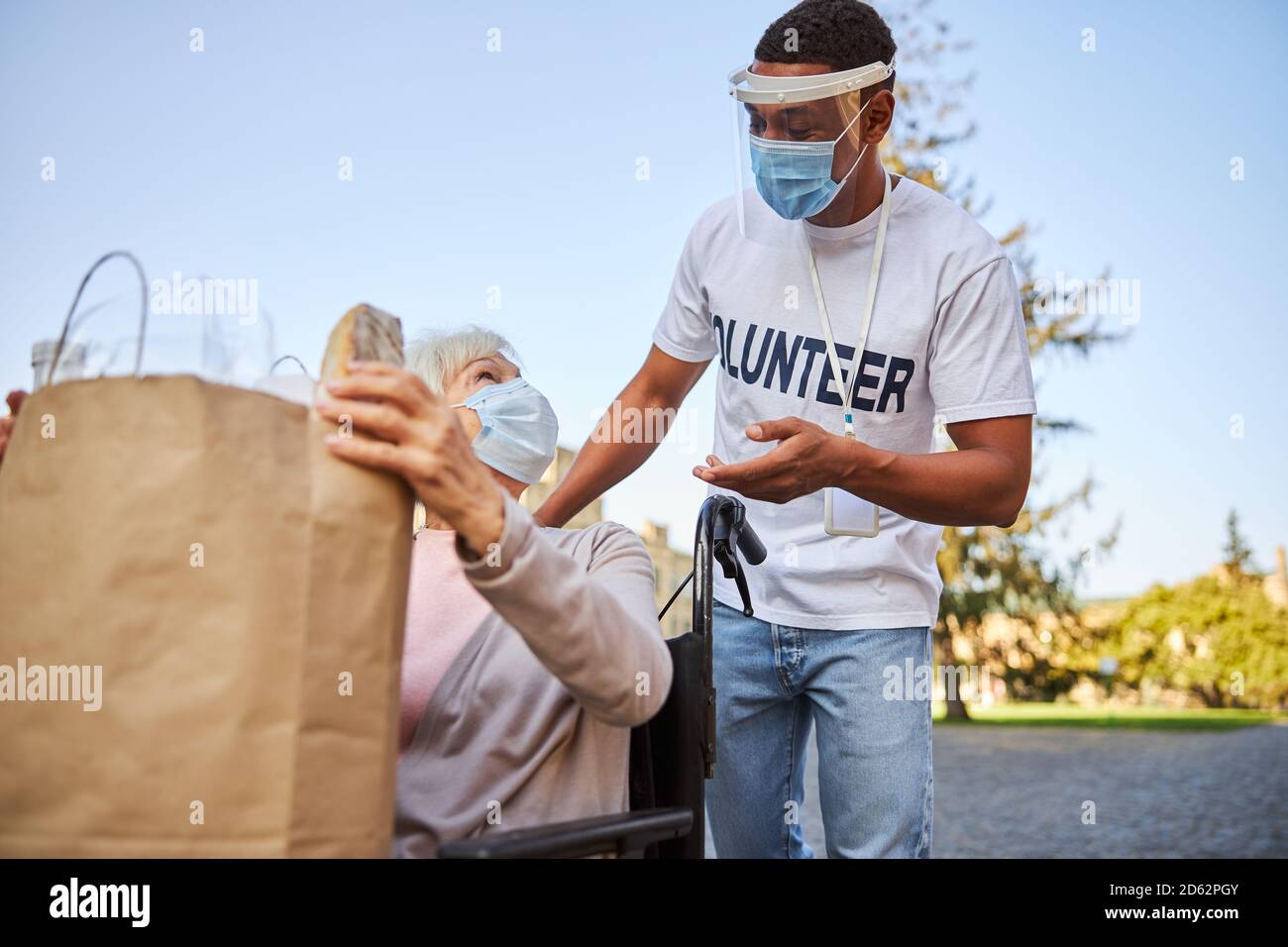 Friendly volunteer addressing aged woman with disability Stock Photo