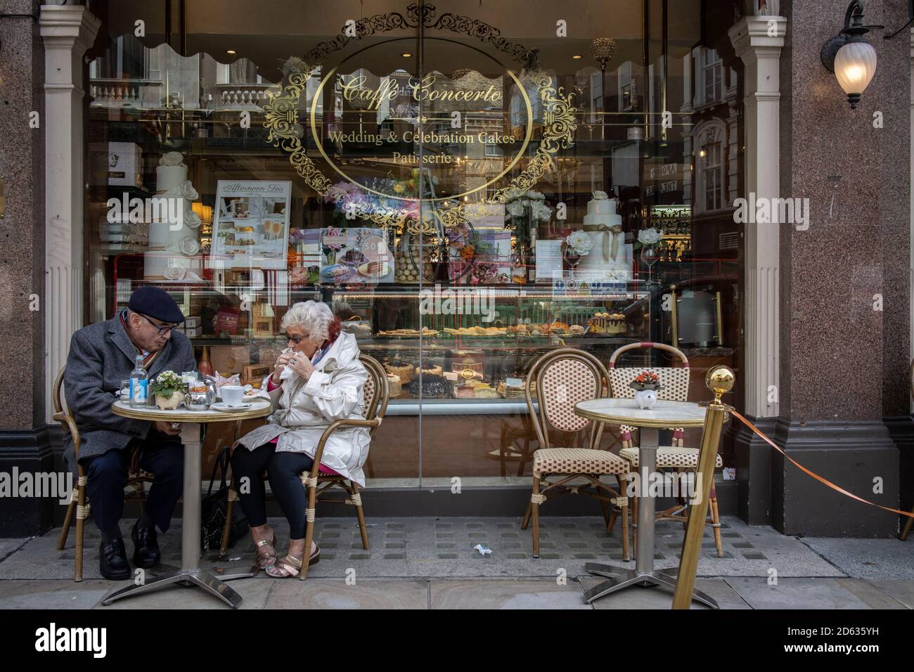 An elderly couple enjoy afternoon tea whilst sat outside Caffe Concerto on Shaftesbury Avenue, heart of London's West End, England UK Stock Photo
