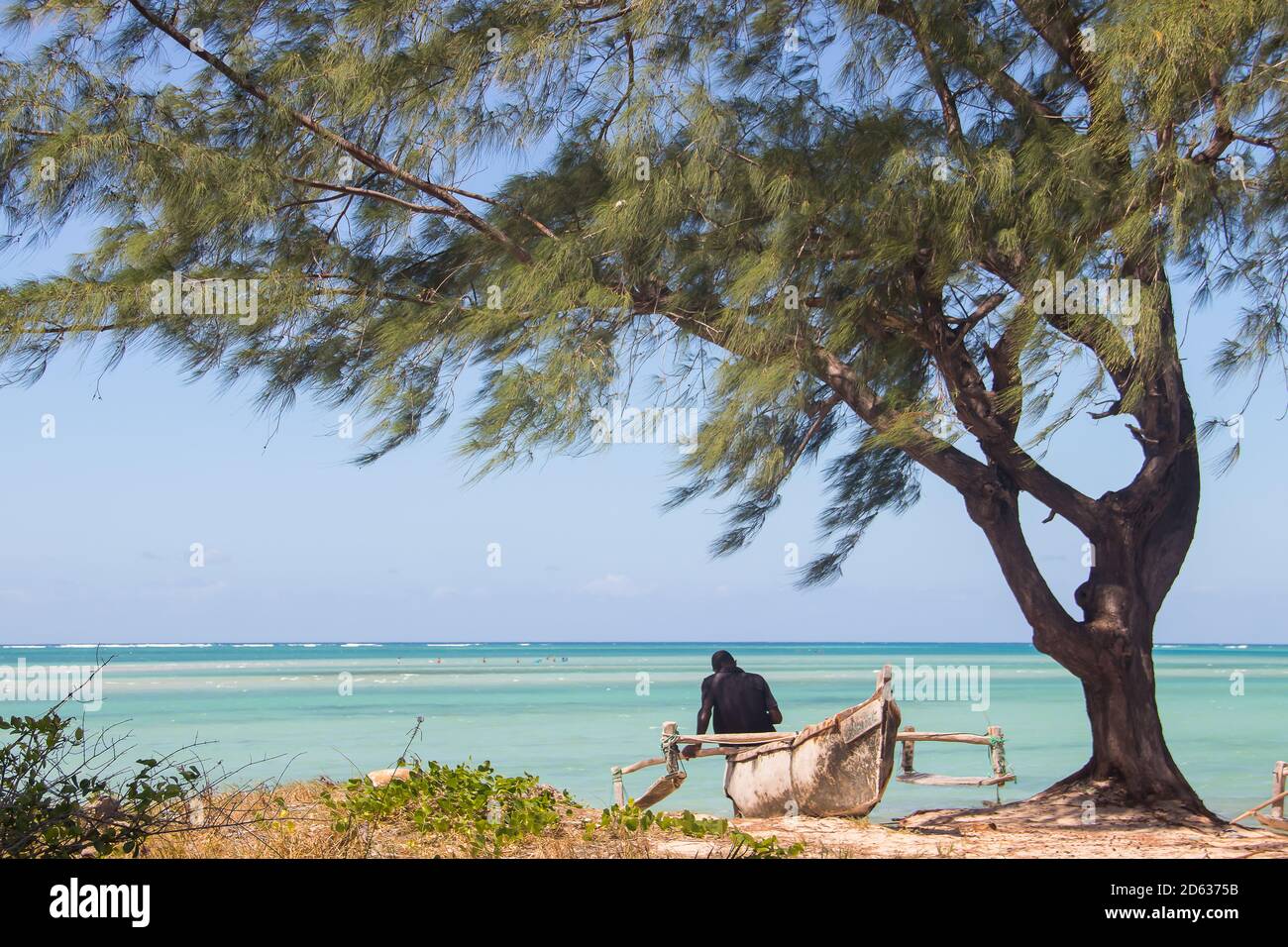Lonely fisherman sitting on his boat at shore of Indian Ocean, waiting for high tide Stock Photo