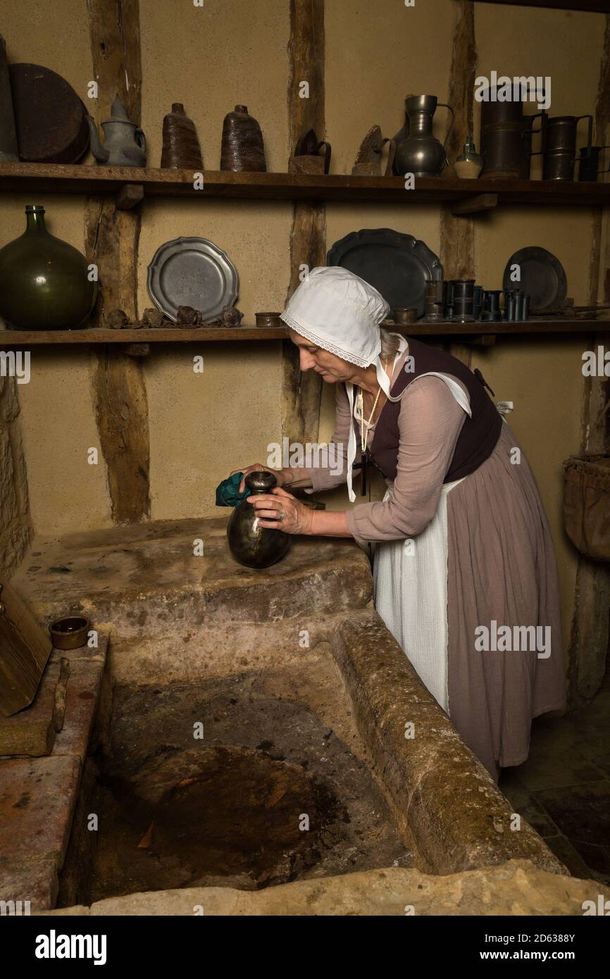 Woman dressed as a medieval peasant maid working in an authentic kitchen in a French castle Stock Photo
