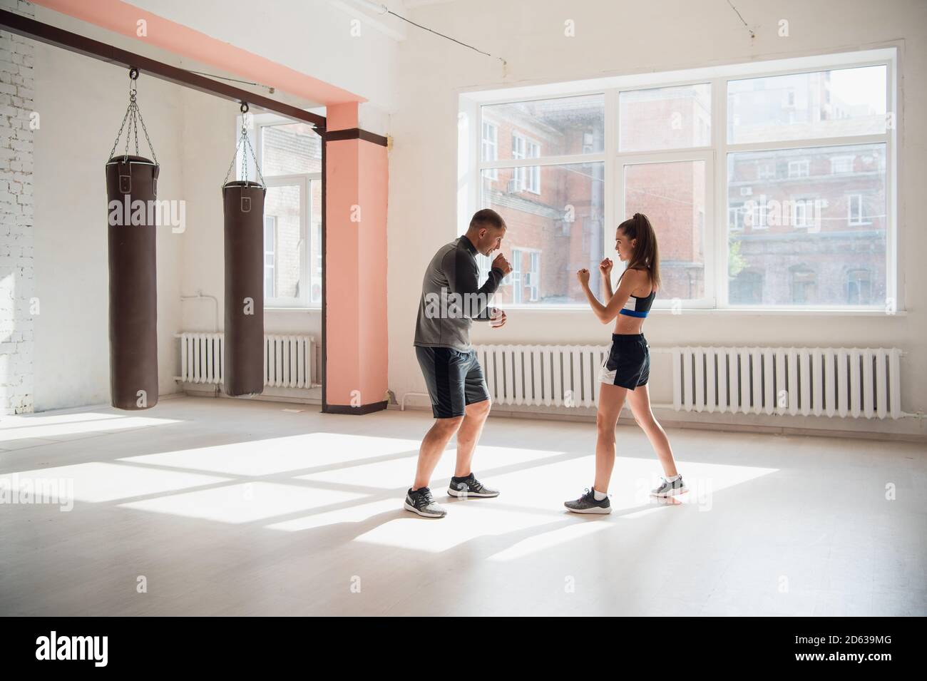 In a spacious loft, a male trainer and his female mentee conduct a boxing training session Stock Photo
