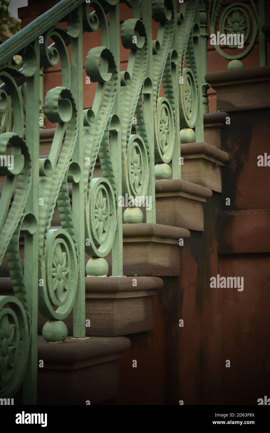 Ornate bronze scrollwork in the railing of an antique stairway Stock Photo