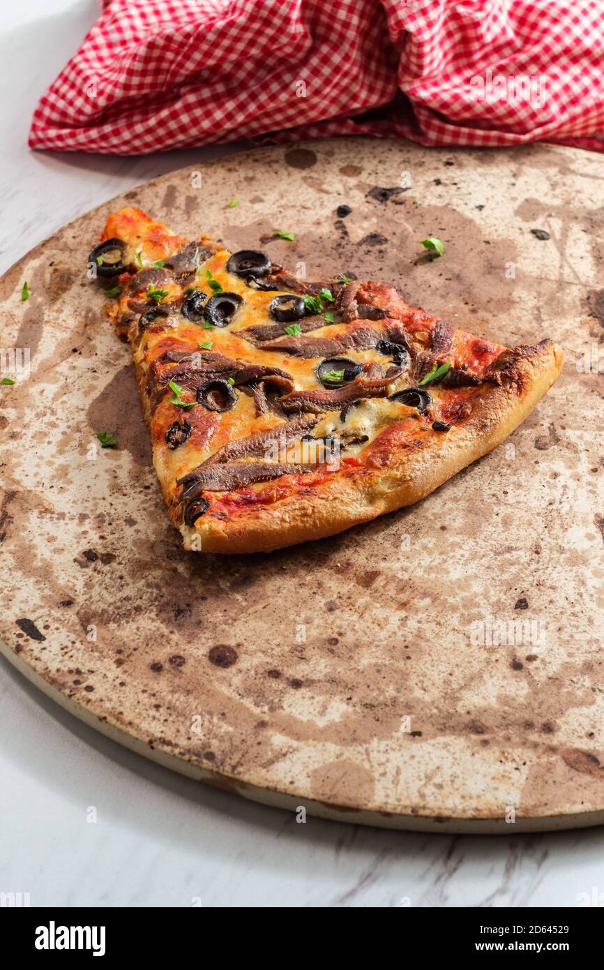 New York style slice of pizza with anchovies and black olives Stock
