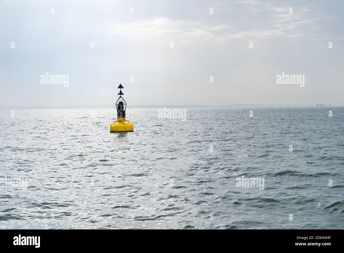 An Electric bollard light or buoy on the open sea in the esuary of the Thames, England, UK with the Red Sands Maunsell Forts in the distance Stock Photo