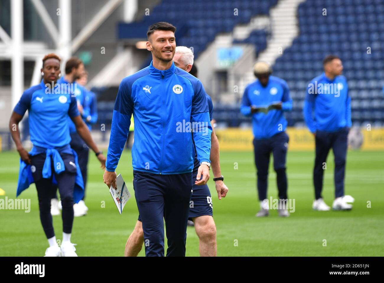 Wigan players read programmes and inspect the pitch prior to kick-off ...