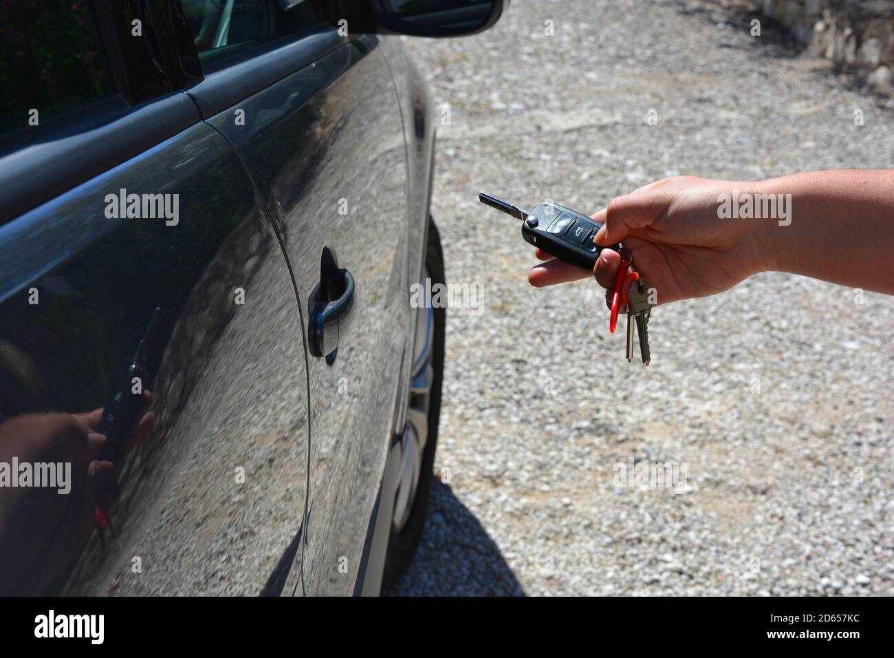 Person using a remote wireless car key to unlock or lock a vehicle, Stock Photo