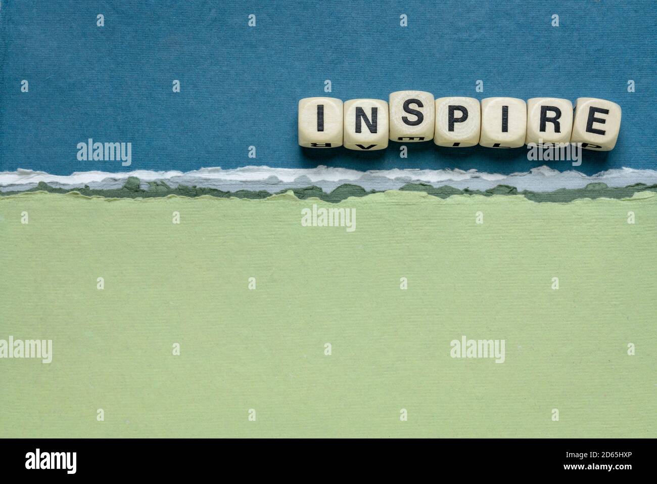 inspire word abstract in wooden letter cubes against handmade paper abstract in blue and green tones, inspiration, leadership and role model concept Stock Photo