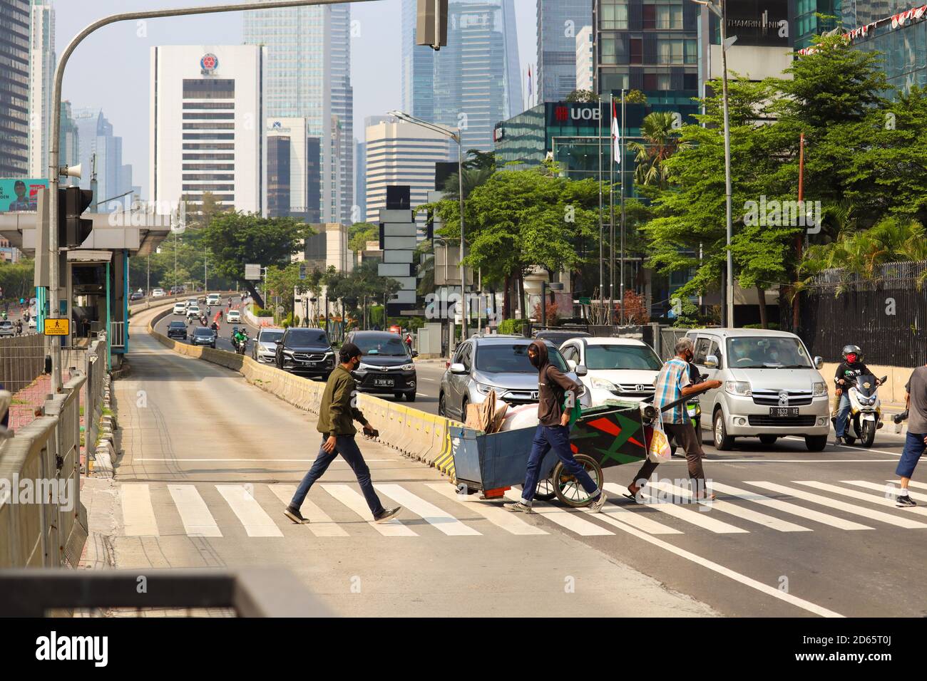 Jakarta / Indonesia - September 5, 2020. a man crossing using a zebra crossing with several cars beside him is stopped. Stock Photo