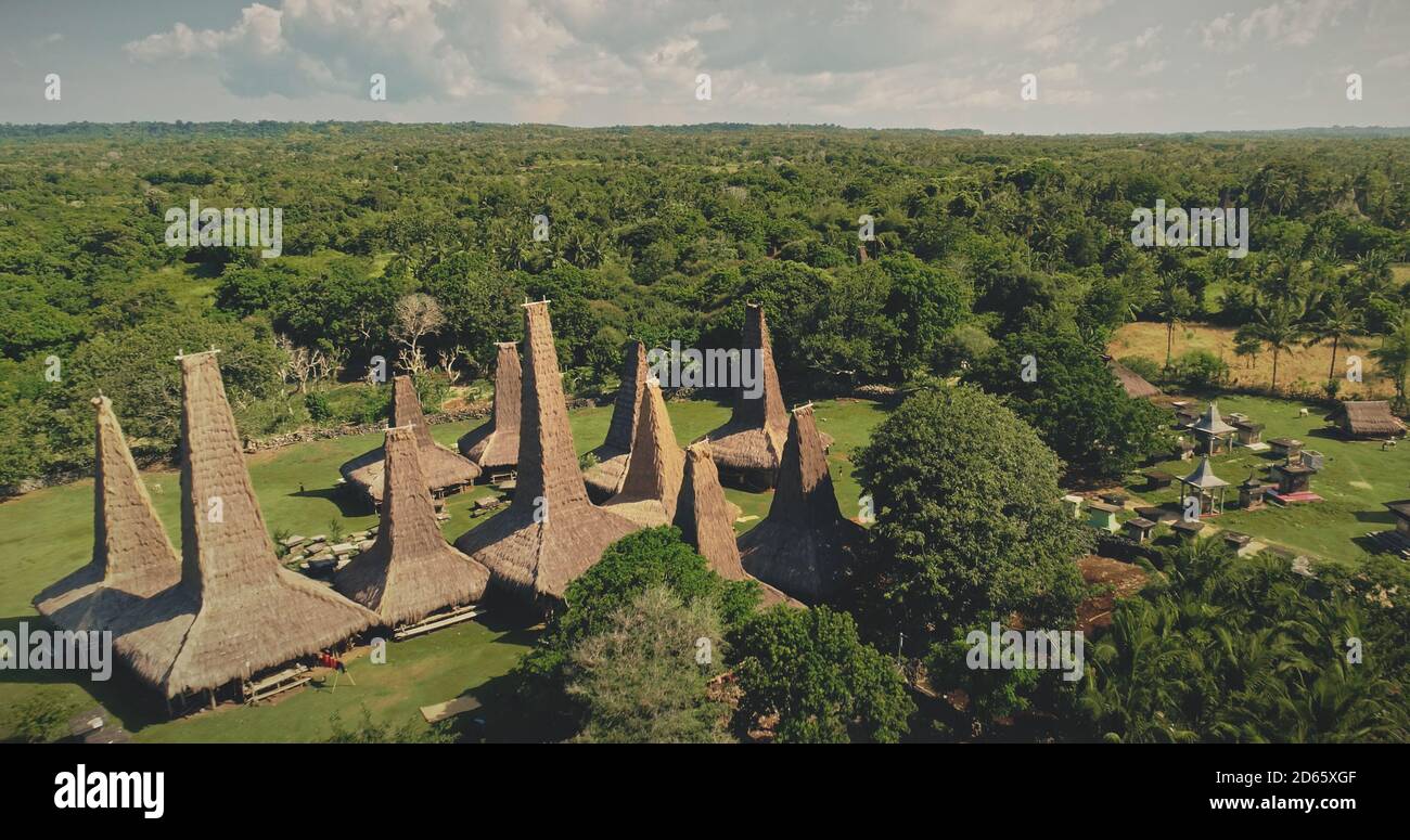 Traditional Indonesia houses at tropical forest with unique roofs aerial view. Authentic local architecture landmark at summer day of Sumba Island, Nusa Tenggara, Asia. Cinematic drone shot Stock Photo