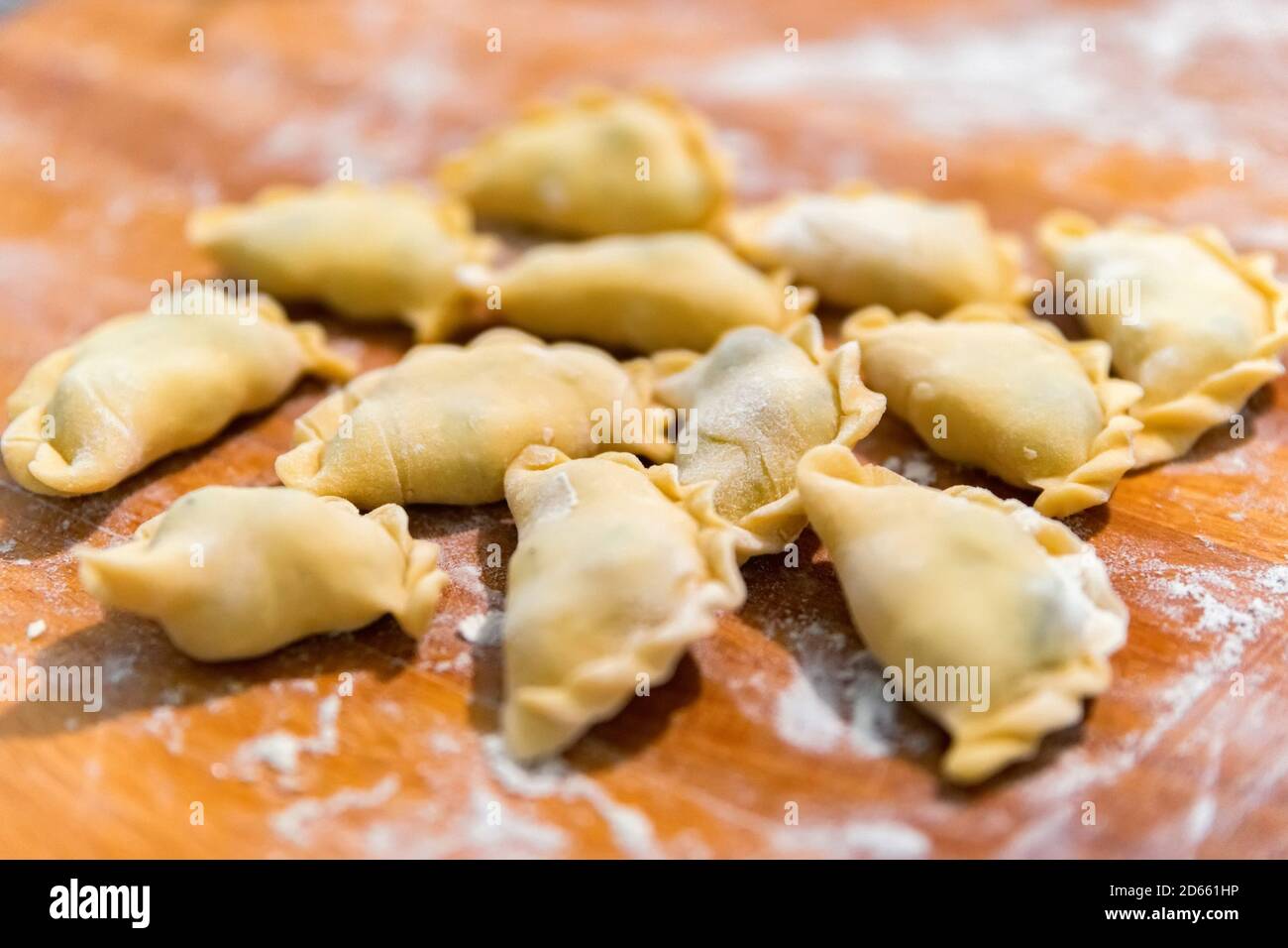 Close-up of perogies from raw dough covered with flour on a wooden cutting board Stock Photo
