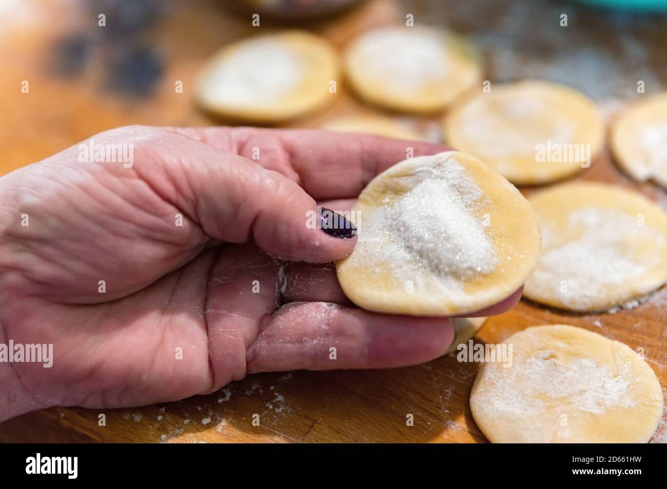 Small crumpets from raw dough covered with flour on a wooden cutting board Stock Photo