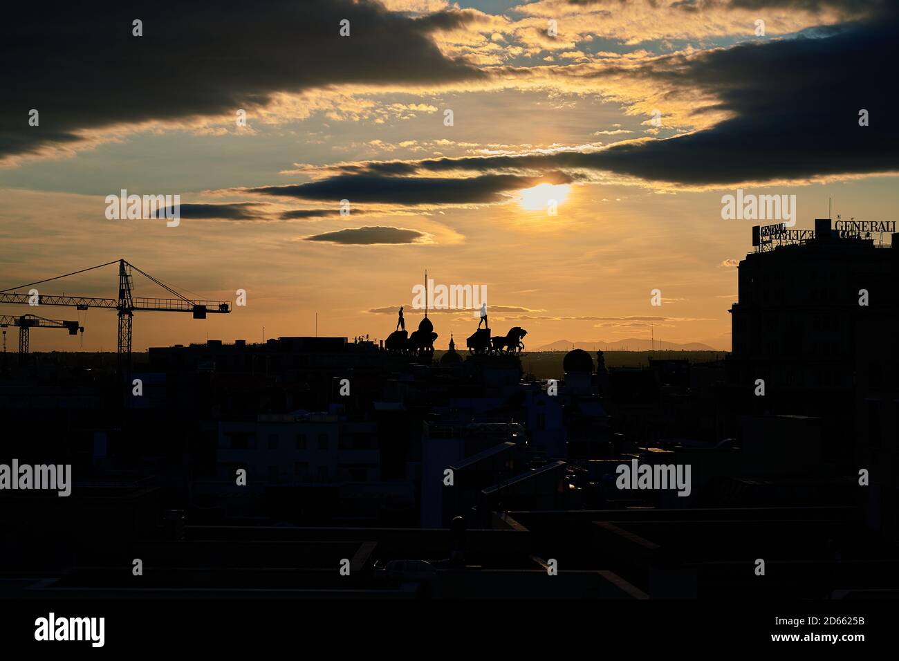 The sun sets over the rooftops and horse and chariot statues of Calle Alcala, Madrid, Spain, September 2020 Stock Photo