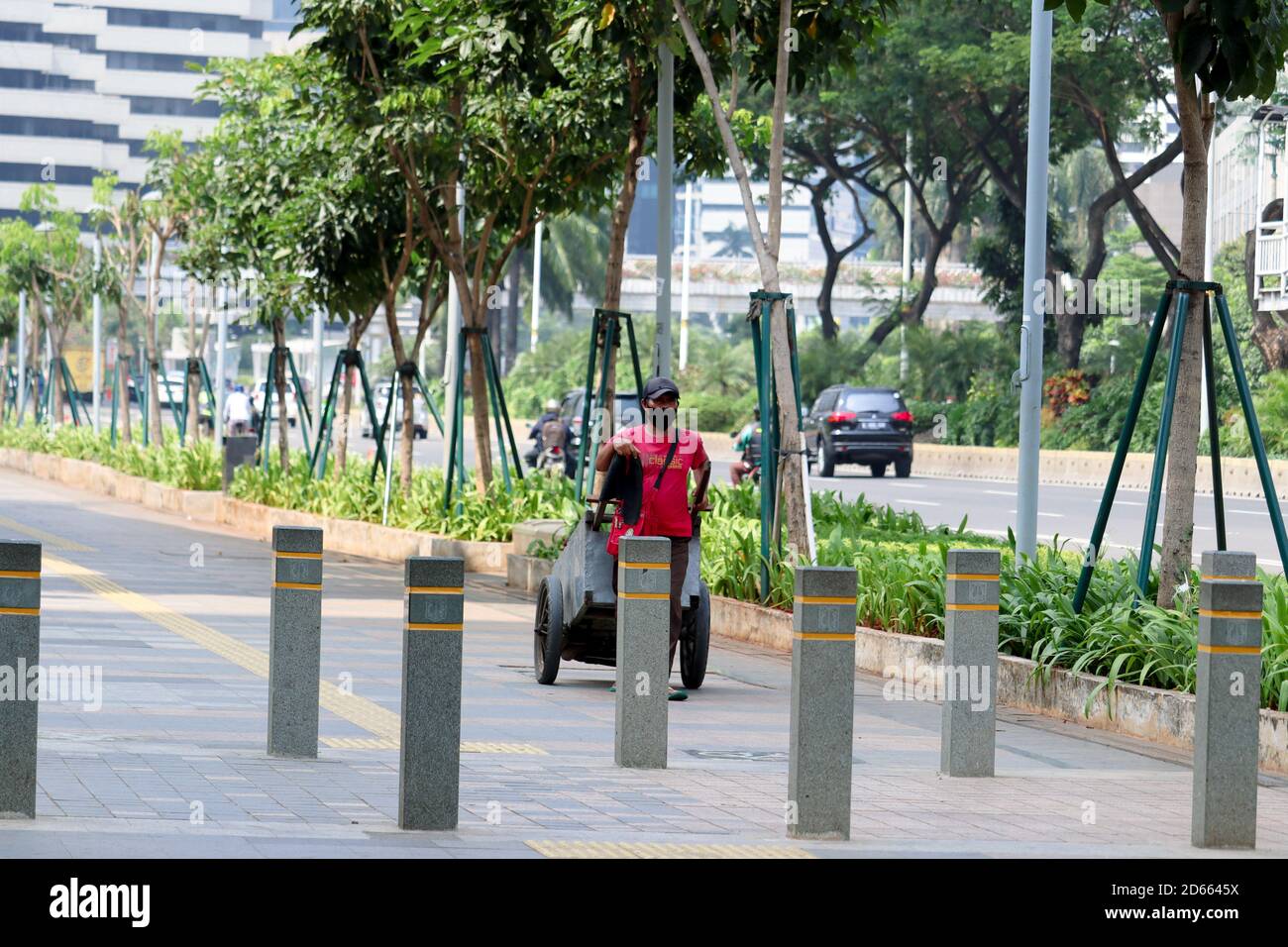 Jakarta / Indonesia - September 5, 2020. a man in red who is pulling a cart on the pedestrian street of Sudirman, Jakarta Stock Photo