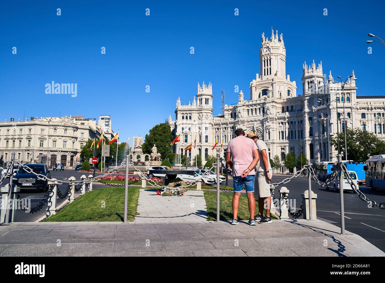 Two men in shorts look at the COVID-19 victim memorial flame at Cibeles Palace of communications, Madrid, August 2020 Stock Photo