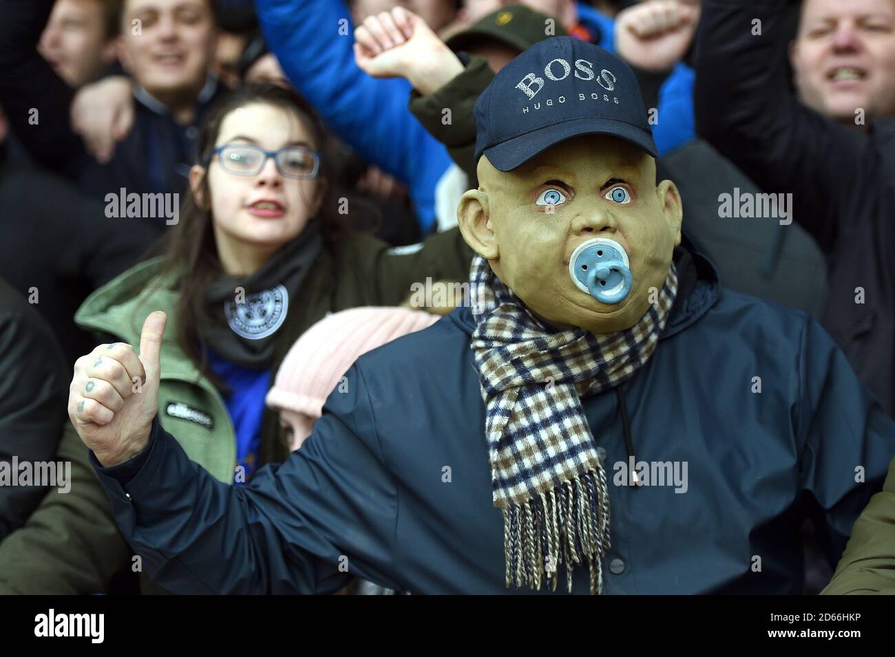 A football fan wear a baby mask in the stands during the match Stock