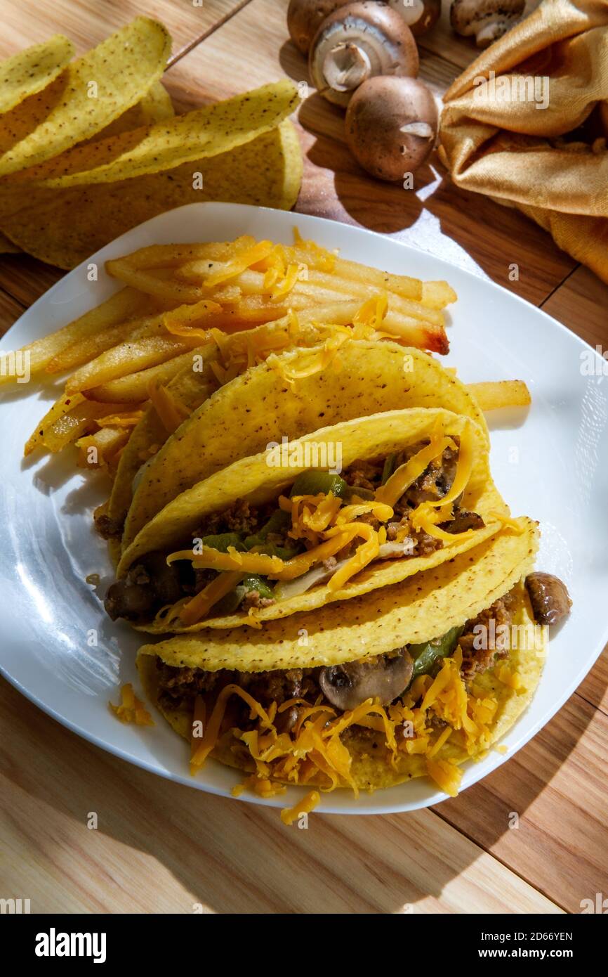 Mexican-American fusion Philly Cheesesteak tacos with onions peppers and mushrooms, fries on the side Stock Photo