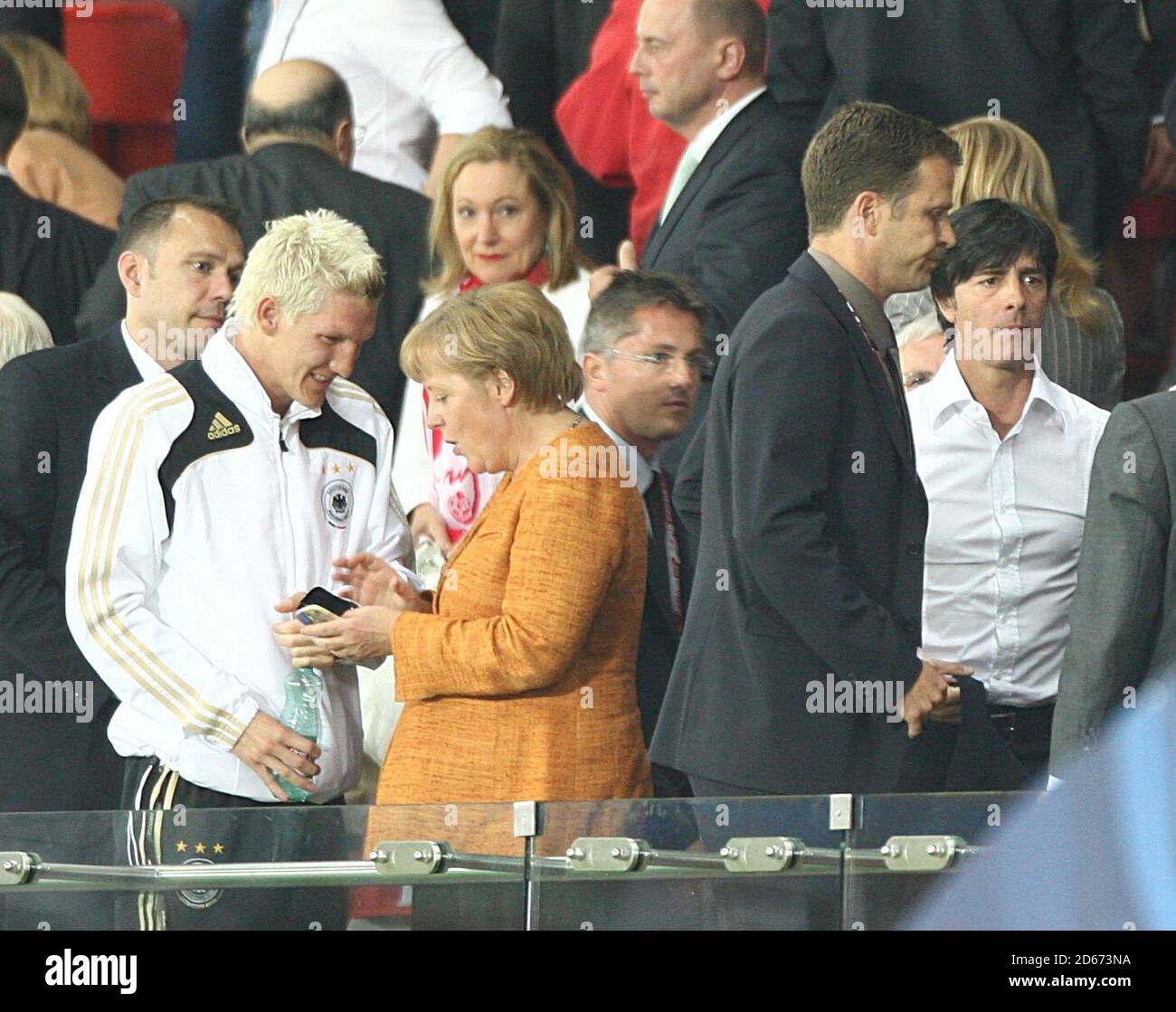 Germany's coach Joachim Low (r) walks by as Germany's Bastian Schweinsteiger talks to German Chancellor Angela Merkel (c) Stock Photo