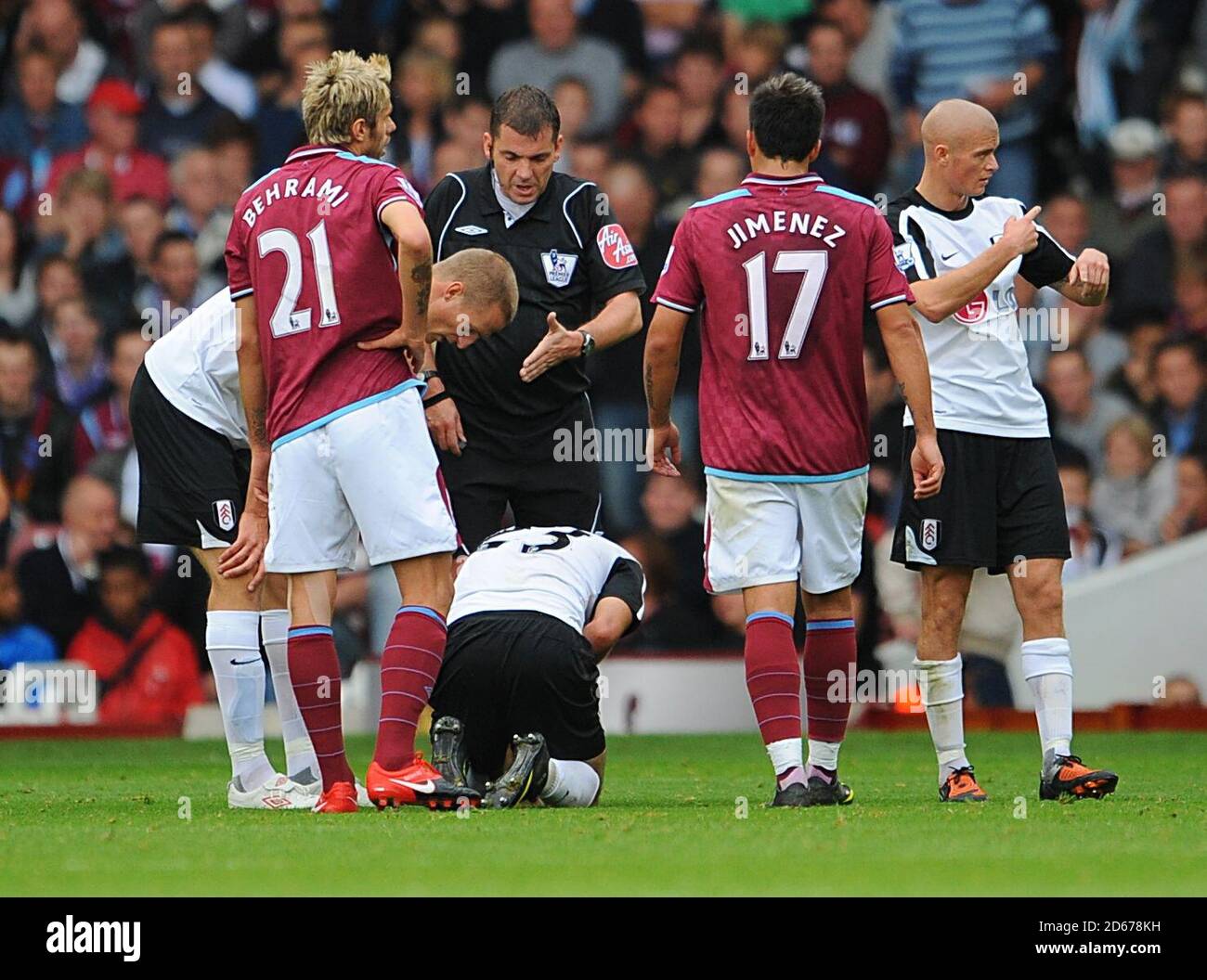 Fulham's Clint Dempsey (centre) kneels on the ground after suffering an injury. Stock Photo