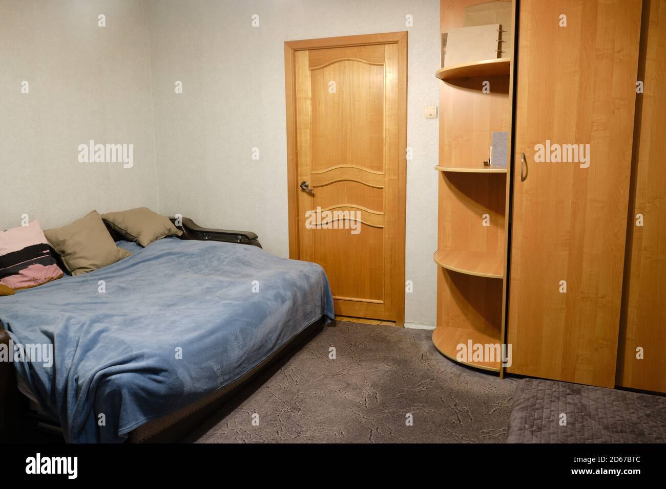 Large made-up bed with pillows, wardrobe and door to the living room Stock Photo