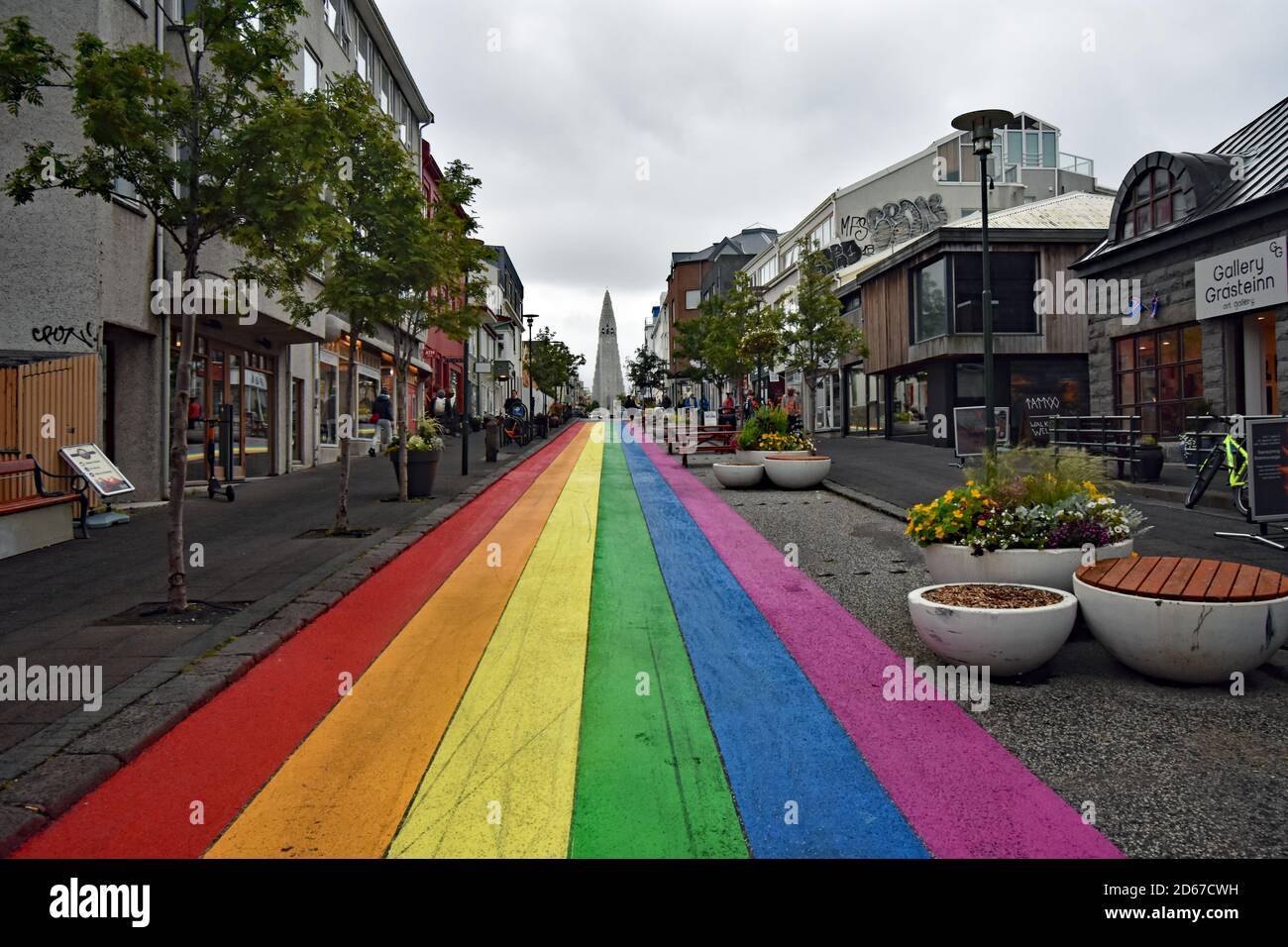 A brightly coloured rainbow painted road (Skolavordustigur) leads to Hallgrimskirkja Church in Reykjavik, Iceland. Pictured on a cloudy overcast day. Stock Photo