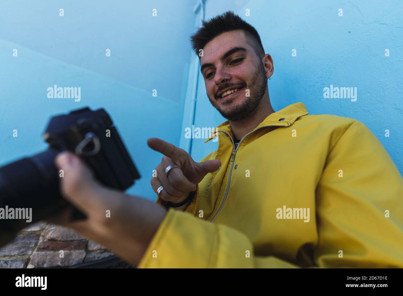 Pusle Using His Camera Male using his camera while sitting by a blue wall Stock Photo - Alamy