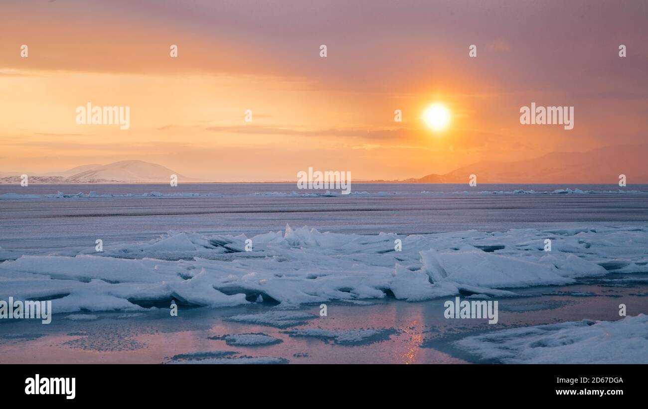 Beautiful view of frozen Lake Sevan on a winter day during the orange sunset Stock Photo