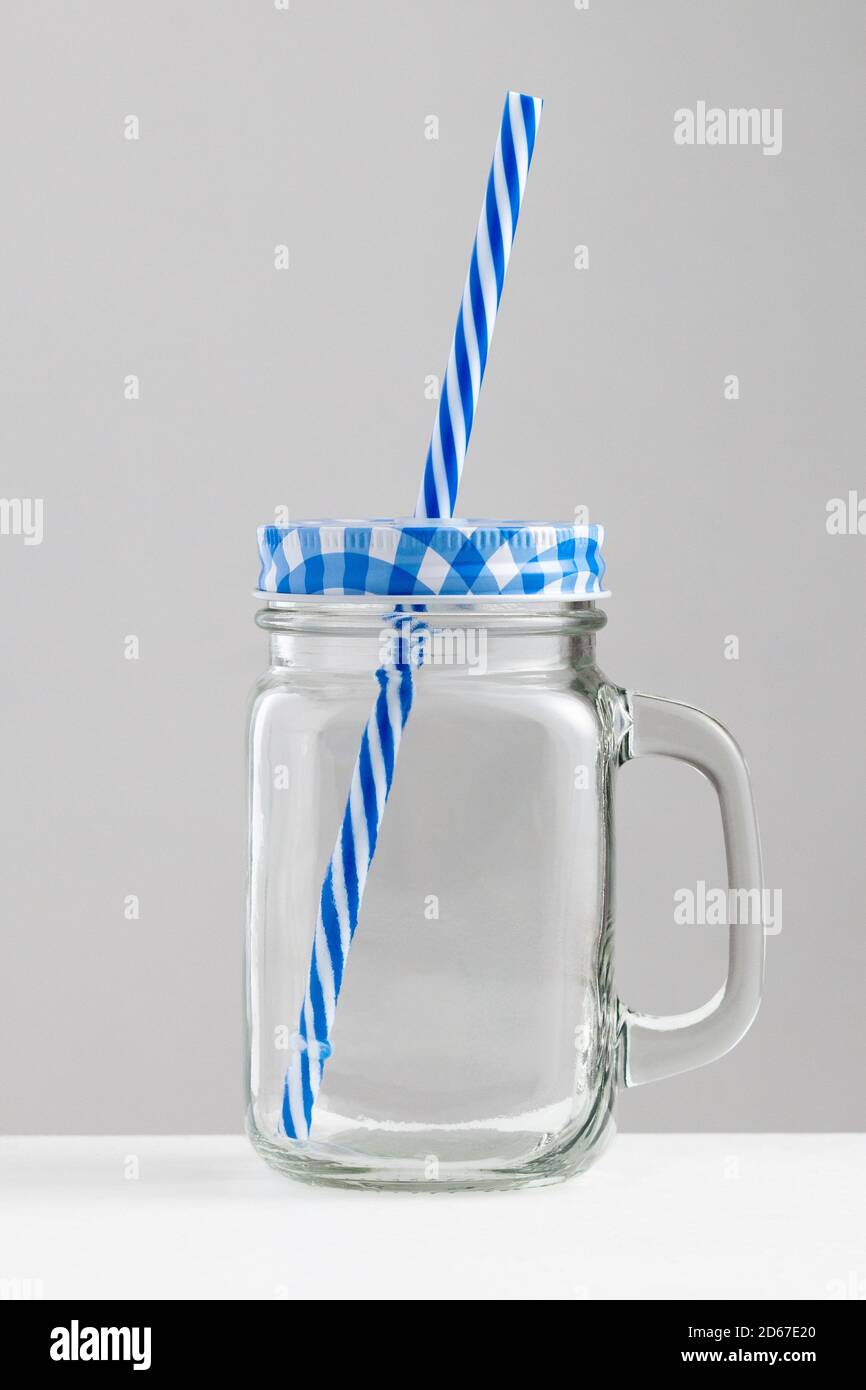 https://c8.alamy.com/comp/2D67E20/beach-glass-cup-with-blue-top-and-blue-straw-on-white-table-with-gray-white-background-2D67E20.jpg
