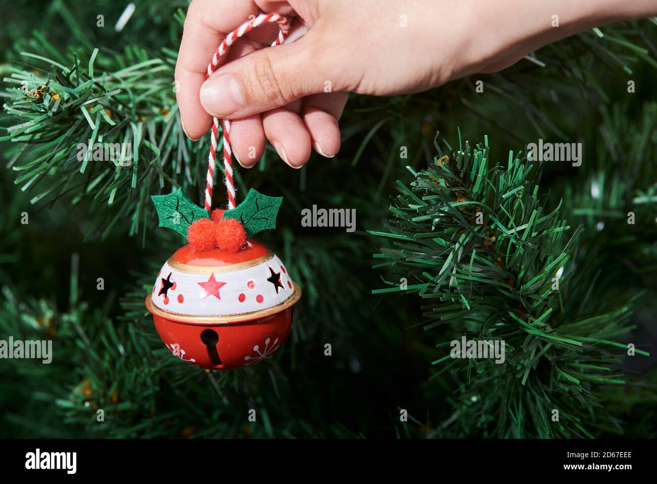 Hand of a young caucasian woman hanging a traditional ornament on a Christmas tree Stock Photo