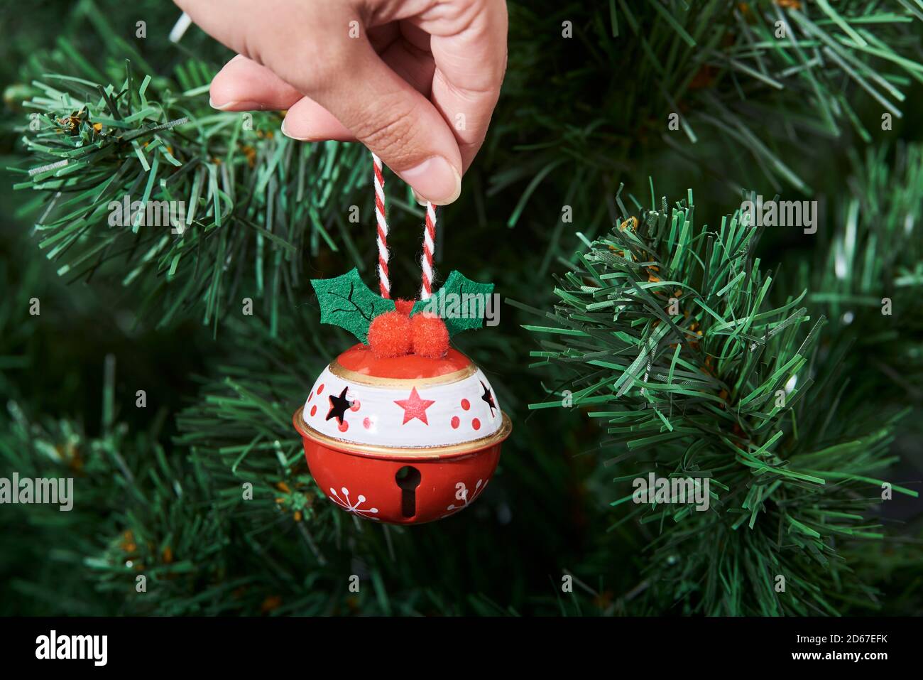 Hand of a young caucasian woman hanging a traditional ornament on a Christmas tree Stock Photo