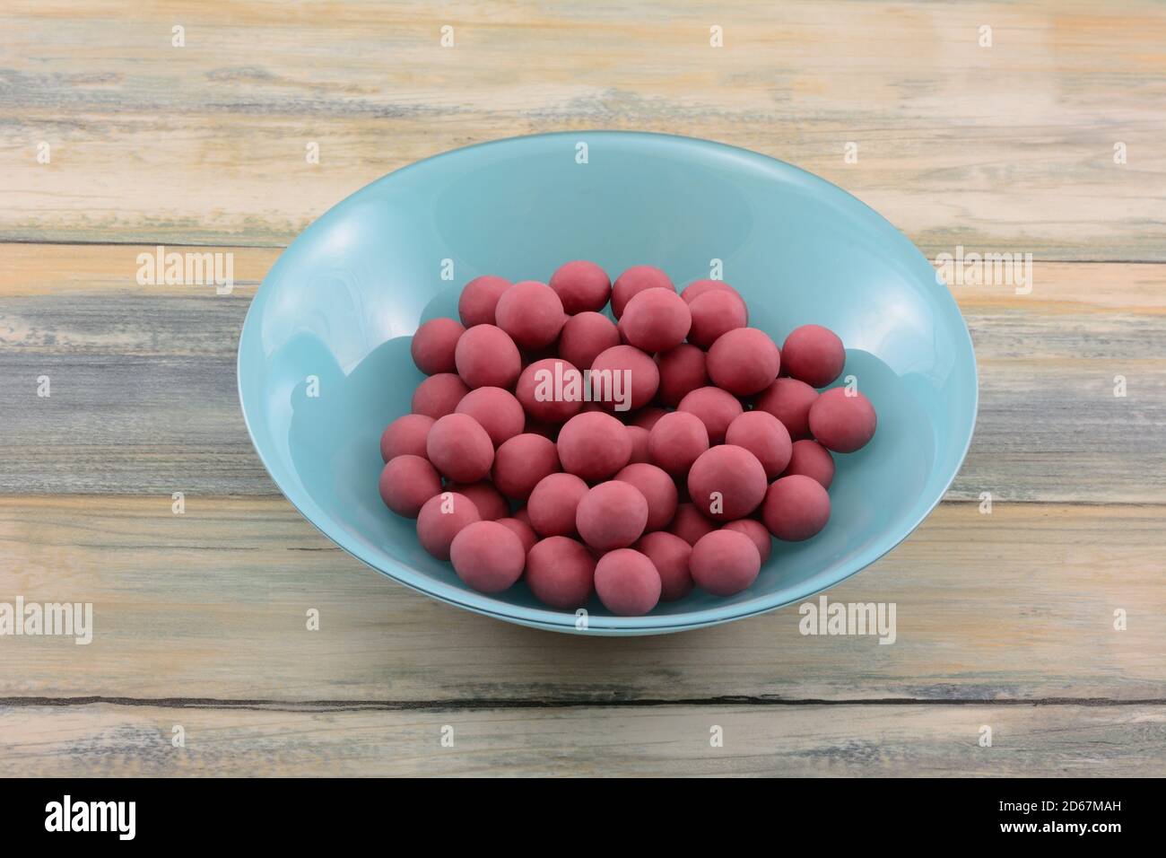 Blueberries dipped in ruby cacao chocolate in blue bowl ob table Stock Photo