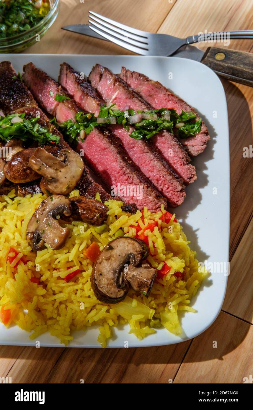 Juicy rare chimichurri verde grilled club steak with yellow rice and