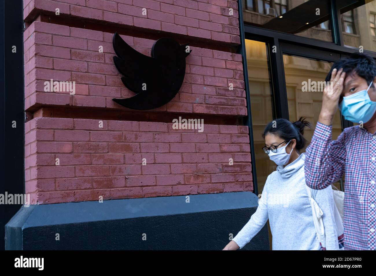 New York, United States. 14th Oct, 2020. People wearing face masks walk past a Twitter logo outside New York City headquarters.Facebook and Twitter took steps to limit the spread of a controversial New York Post article critical of Joe Biden, sparking outrage among conservatives and stoking debate over how social media platforms should tackle misinformation ahead of the US election. Credit: SOPA Images Limited/Alamy Live News Stock Photo