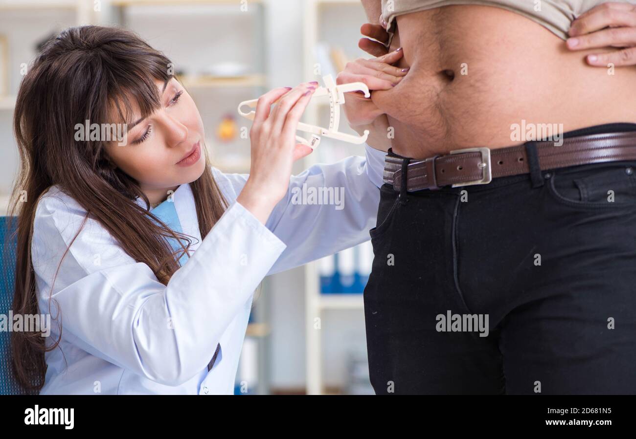 The doctor dietician giving advices to fat overweight patient Stock