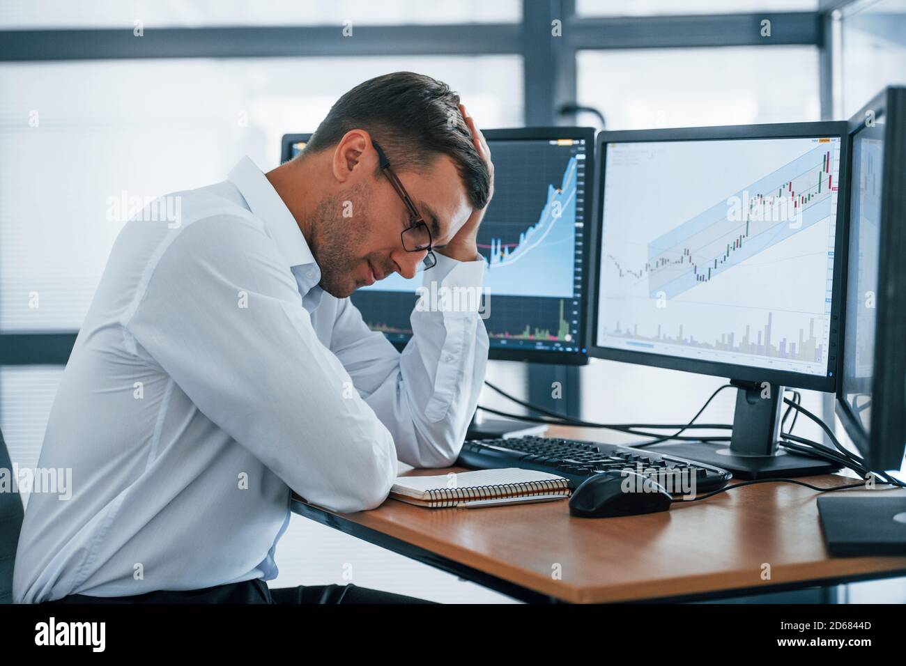 Works with documents. Young businessman in formal clothes is in office with multiple screens. Conception of exchange and money Stock Photo
