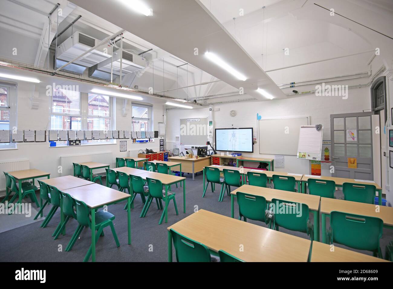 Newly refurbished Victorian school classroom with desks arranged facing the front. Traditional layout reintroduced during the Covid pandemic of 2020. Stock Photo