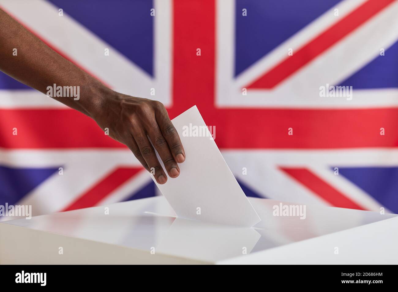 Close-up of African man putting ballot into voting box against the British flag Stock Photo