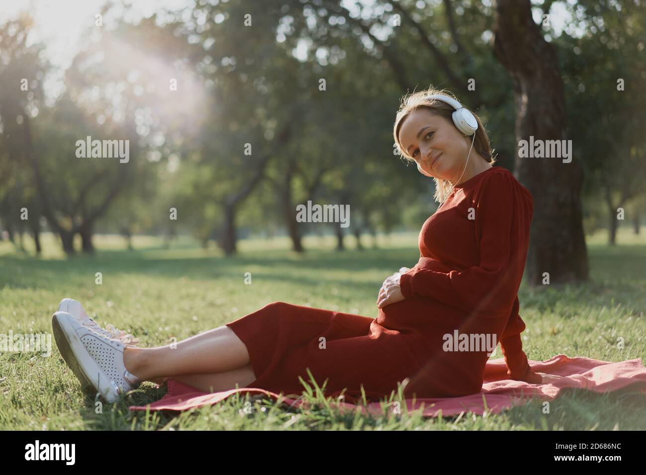 Pregnant woman listening to a music at park Stock Photo - Alamy