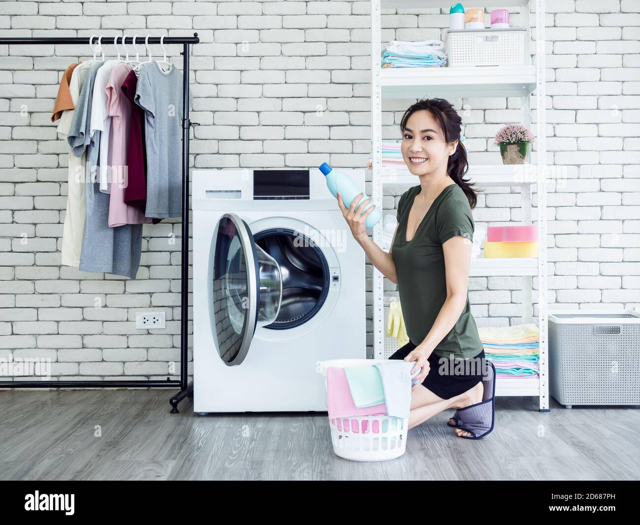 Young Woman Looking At Clean Clothes Out Of Washing Machine In Kitchen  Stock Photo - Alamy