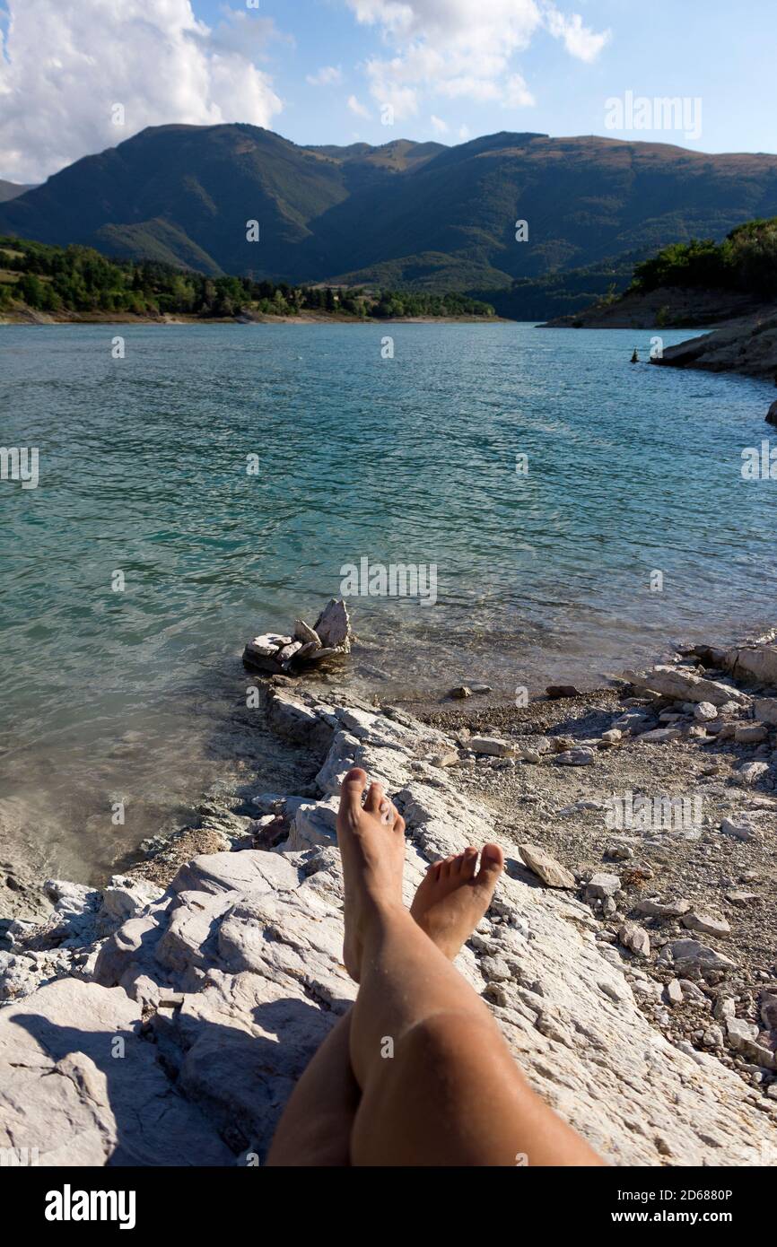 Female legs relaxing in stunning Fiastra Lake.Holidays and local travel concepts.Young woman spends time alone in nature.Menthal ad physical wellbeing Stock Photo