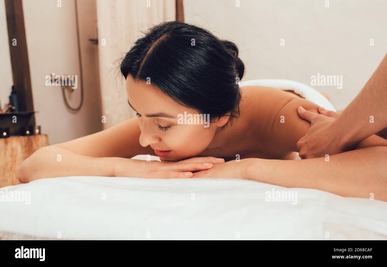 Beautiful woman getting a shoulder and body massage. Mixed race woman relaxing during massage Stock Photo