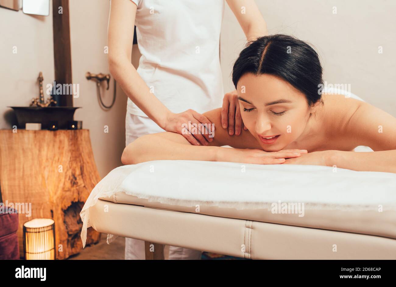 Beautiful brunette enjoying a back massage in an oriental spa salon. Thai body massage Stock Photo