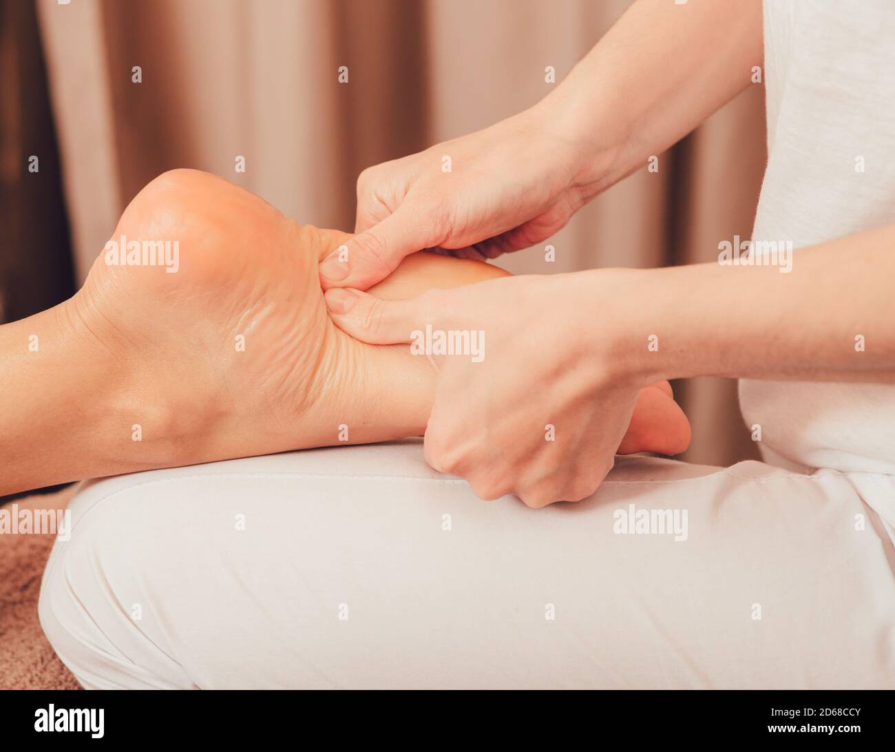 Foot reflexology, foot massage close-up. Masseur pushing on special points on the foot, massage treatment Stock Photo