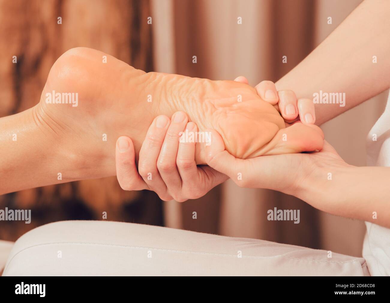 Foot reflexology, foot massage close-up. Masseur pushing on special points on the foot, massage treatment Stock Photo