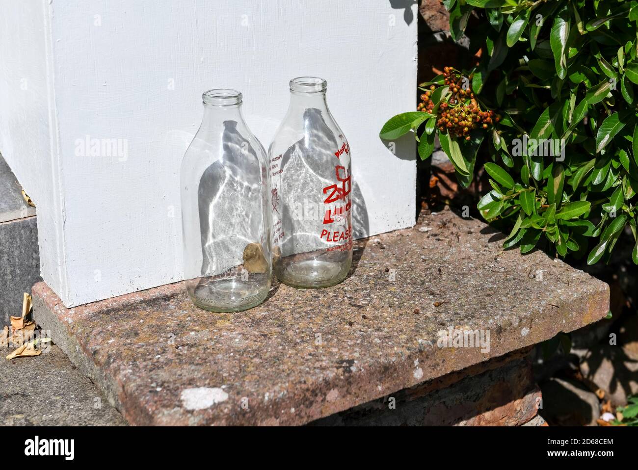 Close up of clean glass empty milk bottles bottle outside a house on a doorstep England UK United Kingdom GB Great Britain Stock Photo