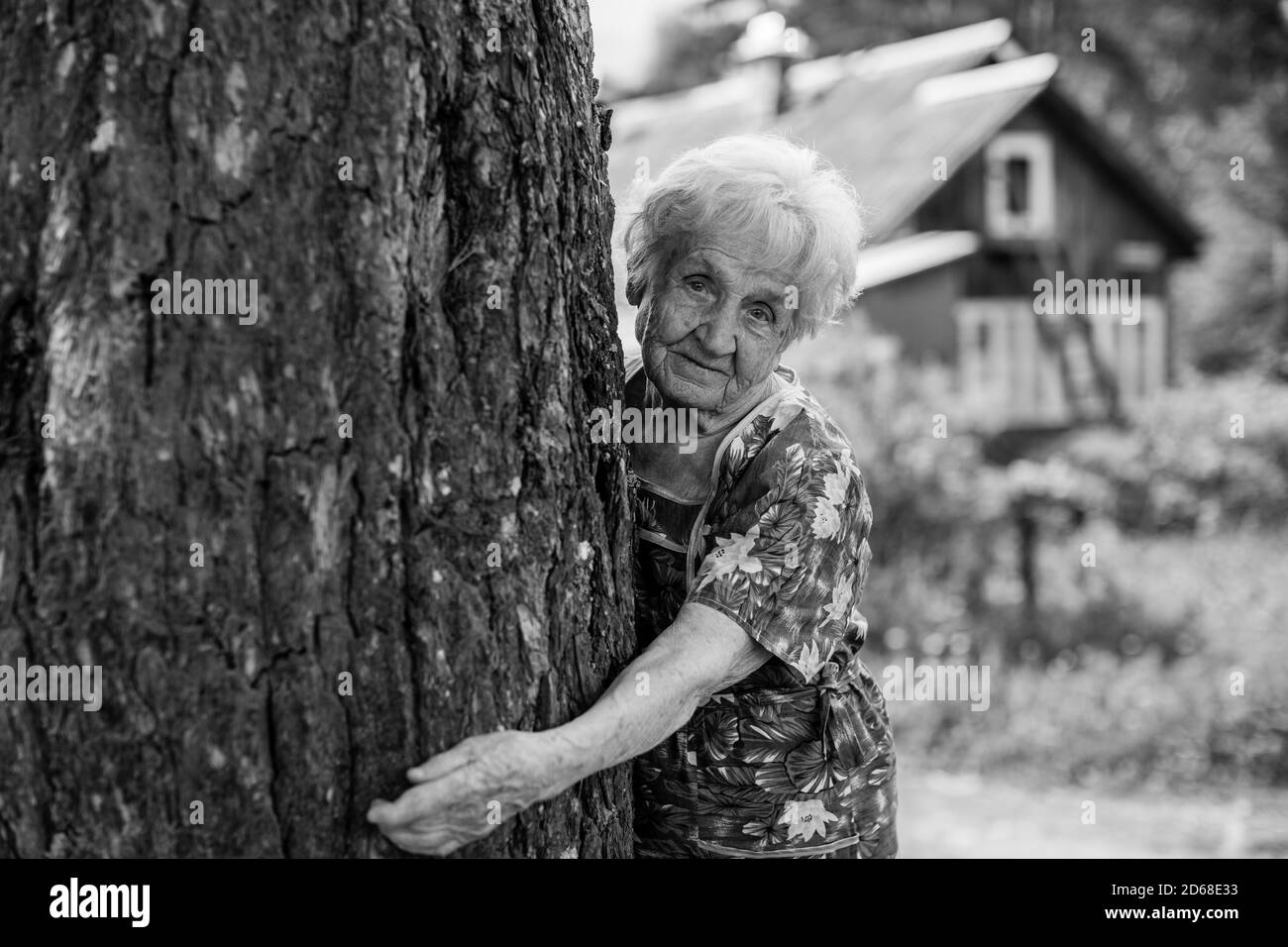 Old woman hugging a tree in the village. Black and white photo Stock ...