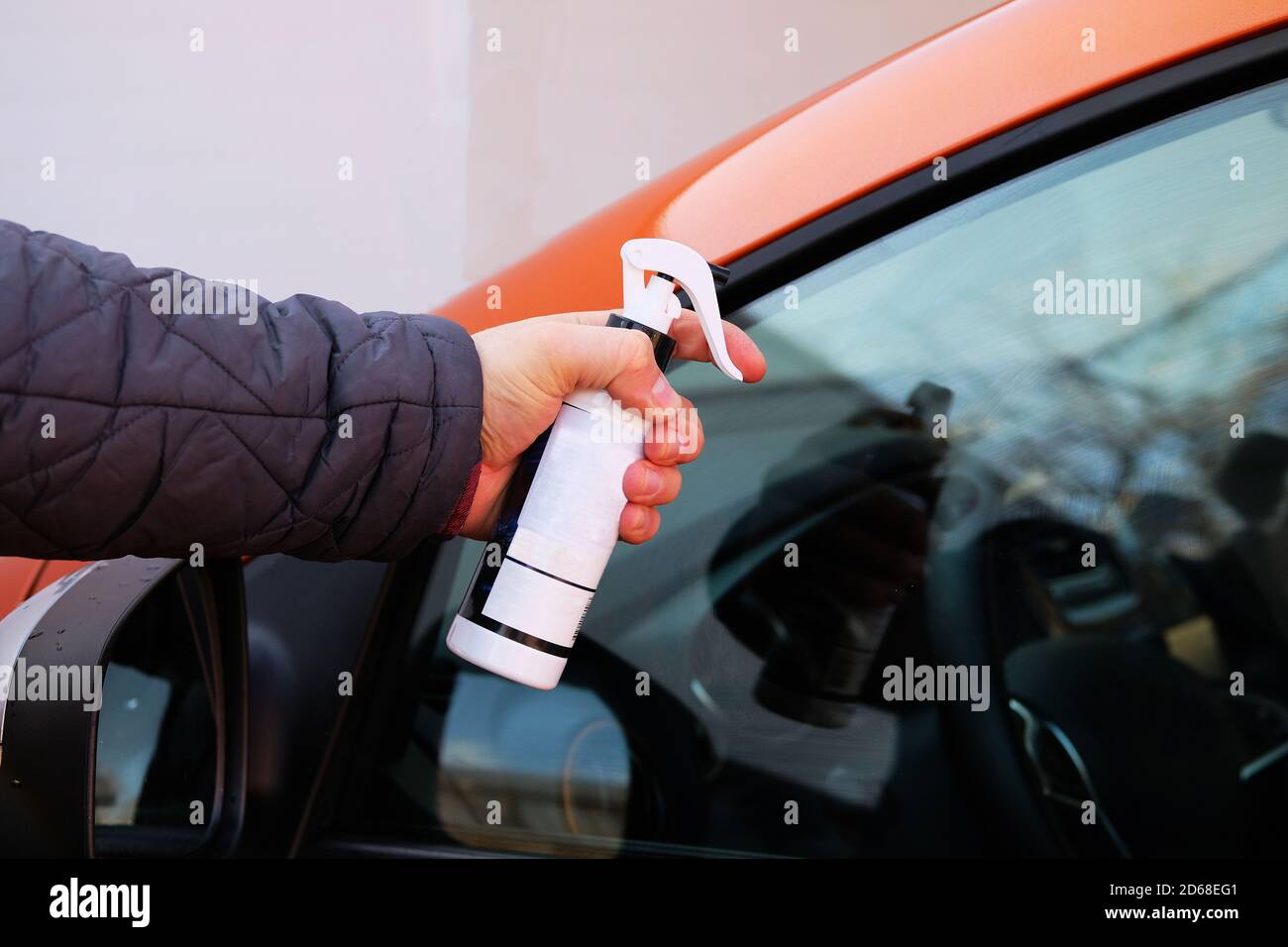 Man after washing uses antirain spray for car glass windows. Male hand
