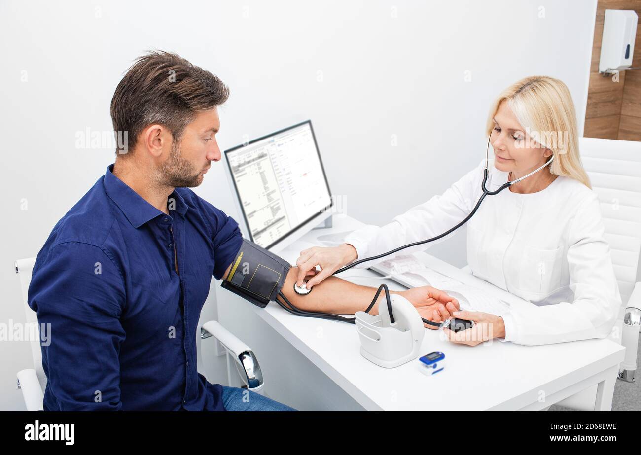 General practitioner measuring arterial blood pressure of a 30-39 old man patient during a medical examination. Prevention and treatment of hypertensi Stock Photo